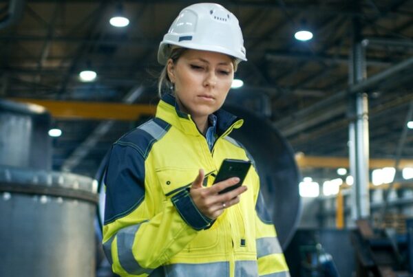 woman in manufacturing building looking at cell phone and safety app